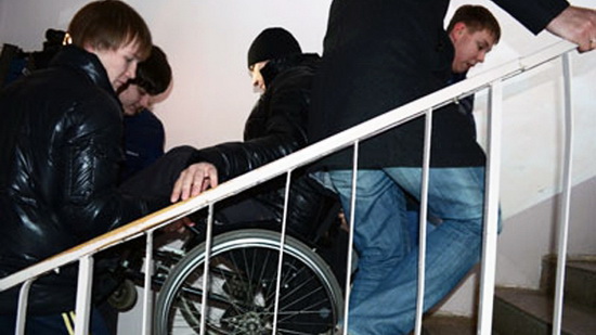 Инвалида колясочника поднимают по лестнице